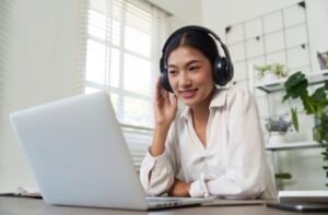 Woman presenting a virtual poster with headphones, smiling at her open laptop